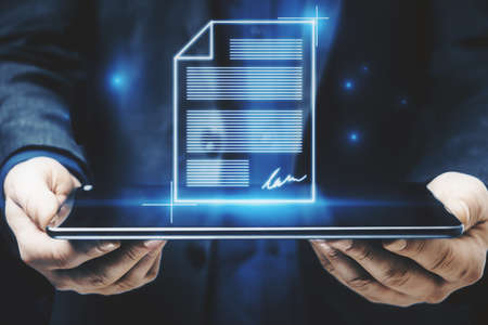 Close up of businessman hands holding tablet with abstract digital document hologram. Electronic...