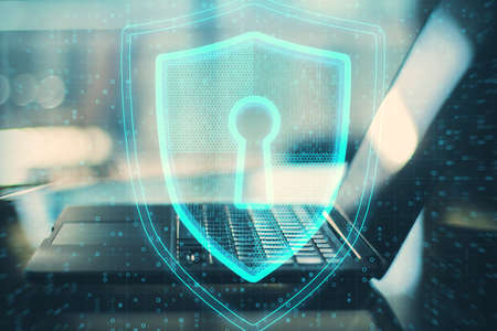Close up of laptop with glowing shield and padlock hud on blurry background. Safety and security...