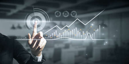 Close up of male hand pointing at abstract glowing business chart on blurry office background....