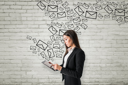Portrait of attractive young european businesswoman using tablet with creative drawn email icons on...