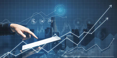 Close up of businessman hand pointing at tablet with glowing business chart grid on blurry city...