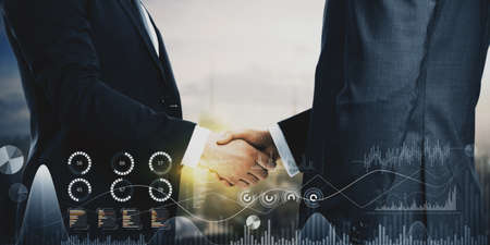 Close up of businessmen shaking hands in city with creative business chart hologram on blurry background. Innovation, teamwork, finance, trade, future, ai and technology concept. Double exposureの写真素材