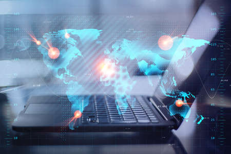 Close up of laptop at desktop with creative glowing map hologram on blurry background. Technology,...