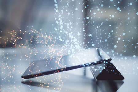 Close up of tablet on desktop with abstract polygonal spheres on blurry office background. Futuristic network and technology concept. Double exposureの写真素材