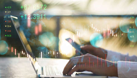 Close up of male hands using laptop and smartphone with creative glowing forex chart on blurry...
