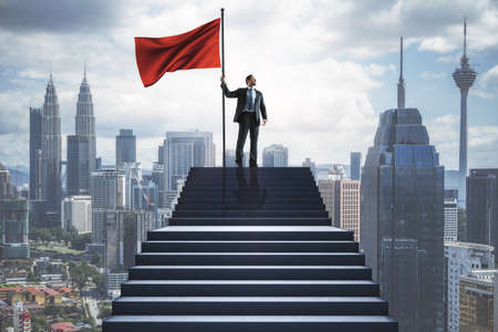 Young european businessman with flag standing on stairs on blurry city background. Success,...