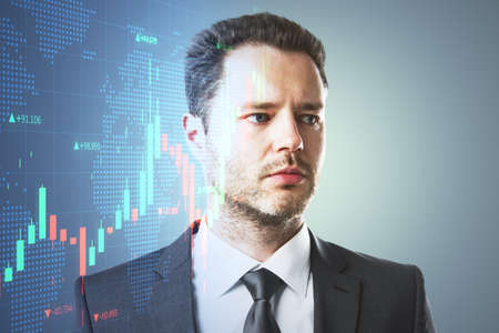 Portrait of handsome young european man thinking about candlestick forex graph and map on gray background with mock up place. Trade, economy and growth concept. Double exposureの写真素材