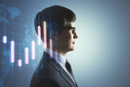 Portrait of attractive young european man thinking about candlestick forex graph and map on gray background with mock up place. Trade, economy and growth concept. Double exposureの写真素材