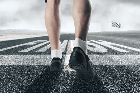 Close up of male legs on creative road reaching finish line with flag on blurry background. Success, challenge and growth conceptの写真素材