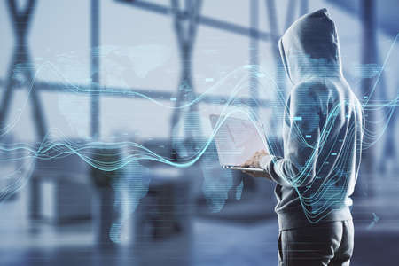 Hacker using laptop in blurry office interior with creative glowing business chart and map hologram on blurry background. Business data, hacking and market concept. Double exposureの写真素材