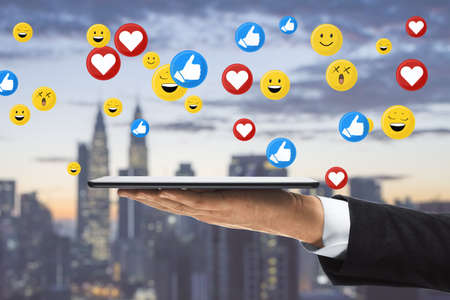 Close up of businessman hand using tablet with social media icons. Blurry bright city background....