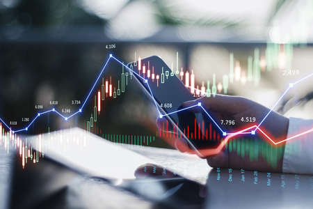 Close up of businessman hand using smartphone with glowing forex chart trading interface on blurry outdoor background with sunlight. Market, economy and data exchange concept. Double exposureの写真素材