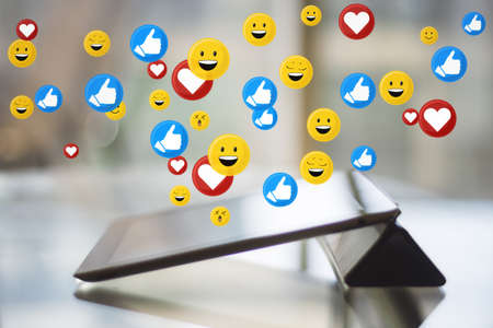 Close up of tablet on desktop with social media icons. Blurry background. Communication, internet...