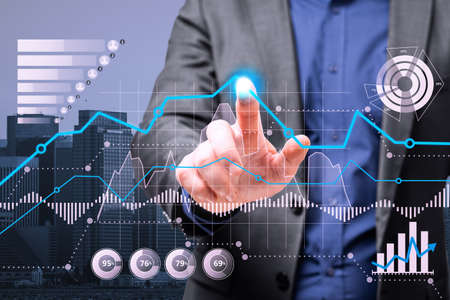Close up of businessman hand pointing at creative business graph hologram on blurry city grid...