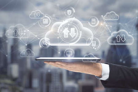 Close up of hand holding tablet with abstract glowing cloud computing hologram with download /...