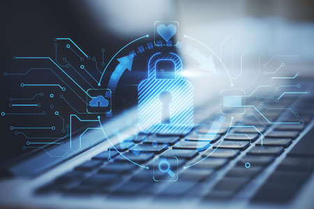 Close up of laptop on desktop with abstract glowing blue padlock hologram on blurry background....