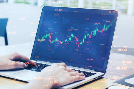 Close up of businessman hands using laptop computer with abstract candlestick forex graph and bid...