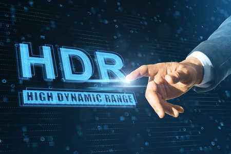Close up of businessman hand pointing at abstract glowing HDR hologram on blue background. High recolution technology conceptの写真素材
