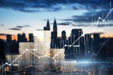 Abstract image of stacked coins and business chart on blurry city background. Finance, economic growth and trade concept. Double exposureの写真素材