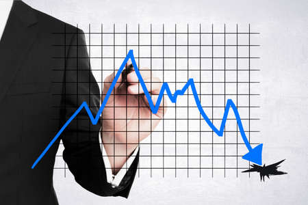 Close up of businessman hand drawing abstract downward falling into hole business chart with arrow...
