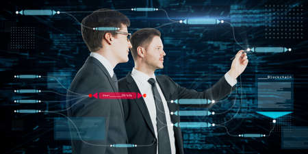 Two attractive european businessmen using abstract glowing big data blockchain interface on dark background. Cryptocurrency, finance, big data and information concept. double exposureの写真素材