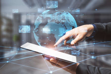 Close up of businessman hand pointing at pad with creative glowing globe hologram with forex charts...