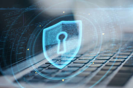 Close up of laptop with abstract glowing keyhole shield interface on blurry background. Protection, safety and technology concept. double exposureの写真素材