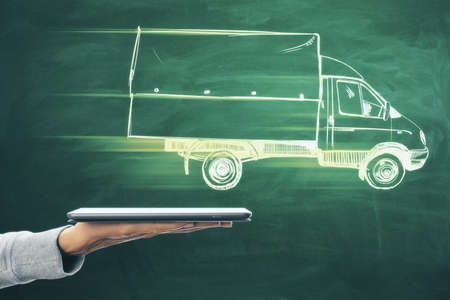 Close up of hand holding smartphone with abstract truck sketch on chalkboard wall background. Online delivery and shipping conceptの写真素材