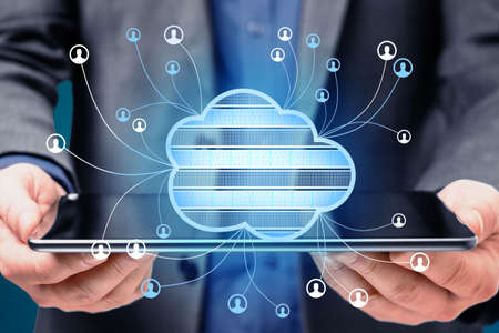 Close up of businessman hands holding tablet with abstract cloud computing hologram on blurry blue...