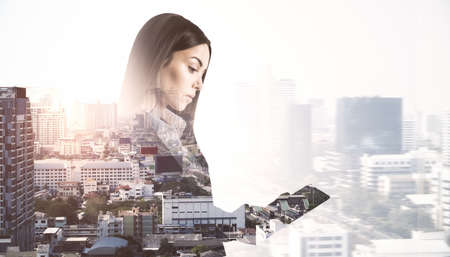 Portrait of attractive thoughtful european businesswoman using smartphone or tablet on bright city...
