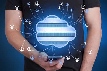 Close up of guy hand holding smartphone with abstract cloud computing hologram on blurry blue...