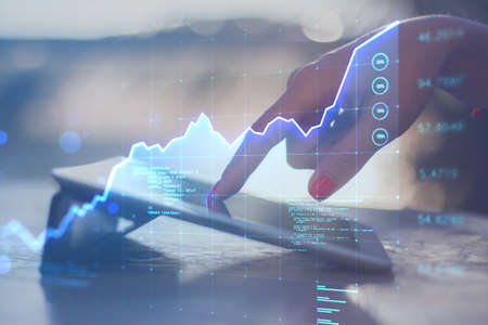 Close up of hand using tablet with abstract glowing business chart hologram on blurry background....