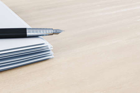 Close up of fountain pen on pile of paperwork on wooden desk top with mock u place. Luxury a,d...
