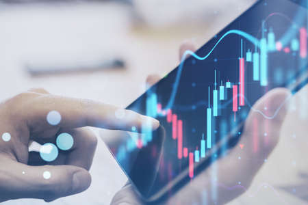 Close up of hand using digital tablet at desktop with glowing forex chart on blurry background....