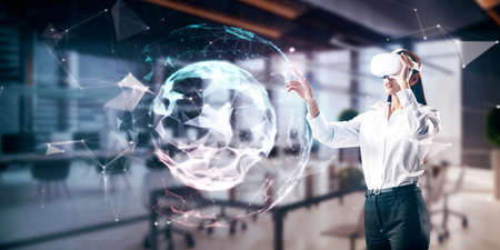 Attractive young european businesswoman with VR glasses using abstract polygonal sphere on blurry...