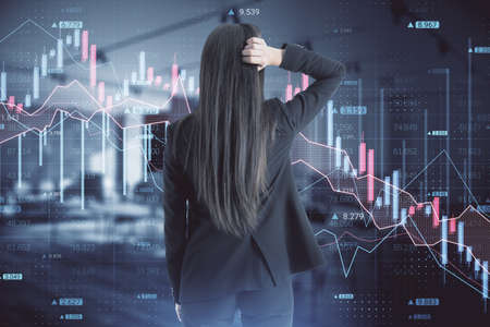 Back view of stressed out businesswoman looking at abstract downward forex chart on blurry office...