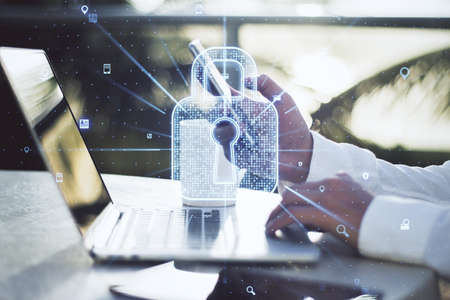 Close up of businessman hand using laptop and smartphone with creative glowing web security padlock...