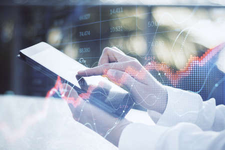 Close up of businessman hand using tablet with abstract red forex chart index on blurry outdoor...