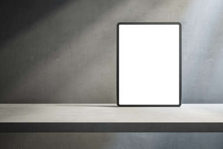 Close up of empty white tablet on desktop and concrete wall background with shadows and mock up...