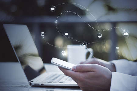 Close up of hand using laptop keyboard and cellphone with abstract SEO search and communication...