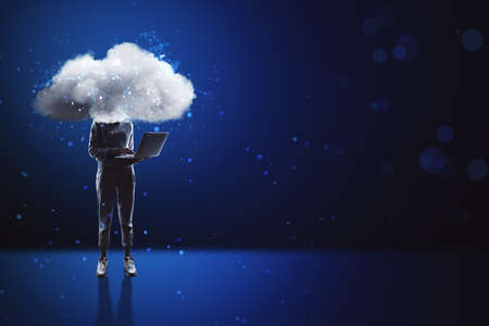 Cloud headed hacker with laptop standing on abstract blue bokeh interior background with mock up...