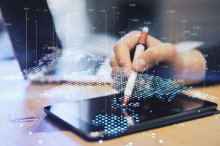 Close up of hand at workplace using tablet with pen and abstract digital map and index lines on blurry background. Global infographic, world and location concept. double exposureの写真素材