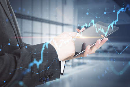 Close up of businessman hand using tablet or smartphone with growing forex chart and dot map...