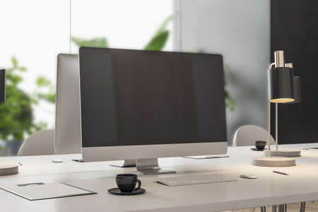 Close up of empty mock up computer screen on desktop in designer coworking office interior with...