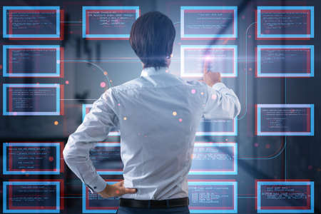 Back view of businessman hand pointing at abstract creative coding programming hologram on blurry...