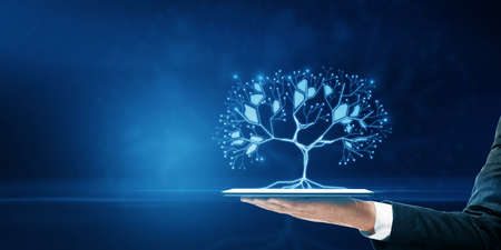 Close up of businessman hand holding tablet with glowing digital polygonal tree on blue background with mock up place. Network, technology and database conceptの写真素材