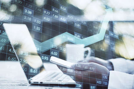 Close up of male hands using mobile phone and laptop at desktop with creative digital financial...