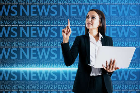Portrait of attractive young european busiesswoman at desktop with laptop on blurry blue breaking news pattern background. Headline, communication and global world concept. double exposureの写真素材