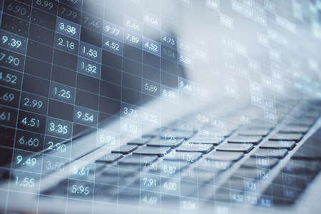 Close up of laptop on desktop with creative digital financial numbers or index data on blurry background. Stock market and growth concept. double exposureの写真素材