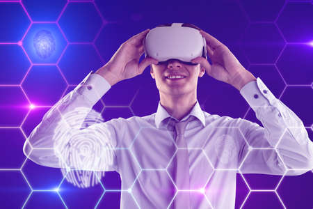 Attractive young european businessman with VR glasses on blue background with digital thumb print...